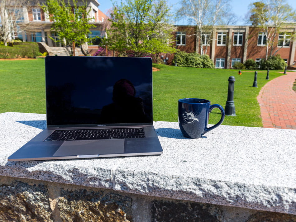 A laptop and coffee mug on the Endicott College campus